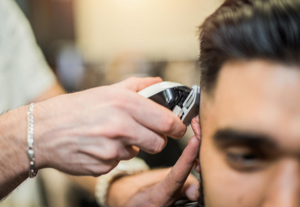 A person getting a haircut with electric clippers from a barber