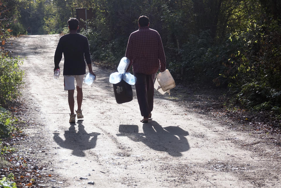 Migrants carry empty water canisters near the Vucijak refugee camp outside Bihac, northwestern Bosnia, Monday, Oct. 21, 2019. Authorities in the town of Bihac on Monday stopped the delivery of water supplies to the Vucjak camp saying they want to draw attention to the problems in the camp set up on a former landfill and near mine fields from the 1992-95 war. (AP Photo/Eldar Emric)