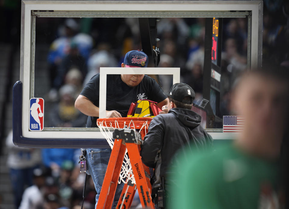 Workers struggle to replace the rim after it was bent during a dunk by Boston Celtics center Robert Williams III in the second half of an NBA basketball game against the Denver Nuggets, Sunday, Jan. 1, 2023, in Denver. (AP Photo/David Zalubowski)