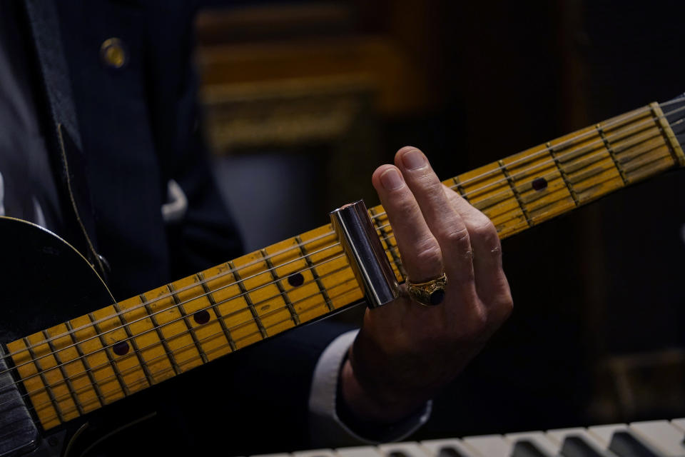 Guitarist and singer Deacon John Moore strums a guitar at his home in New Orleans, Wednesday, May 3, 2023. Moore has been a regular performer at the New Orleans Jazz & Heritage Festival since it began in 1970, and is playing the festival again this year. (AP Photo/Gerald Herbert)