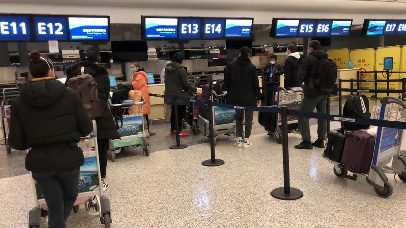 People wait to check in at the airport in Wuhan