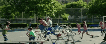 a crowded playground with a parent running across it