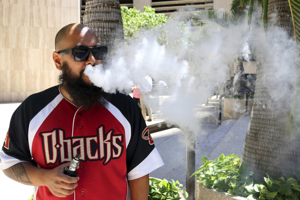 Trevor Husseini exhales a vape cloud in Honolulu on Thursday, March 28, 2019. Hawaii lawmakers are considering outlawing flavored tobacco and electronic cigarette liquids like Maui Mango and Cookie Monsta in an effort to stop escalating teenage vaping. (AP Photo/Audrey McAvoy)