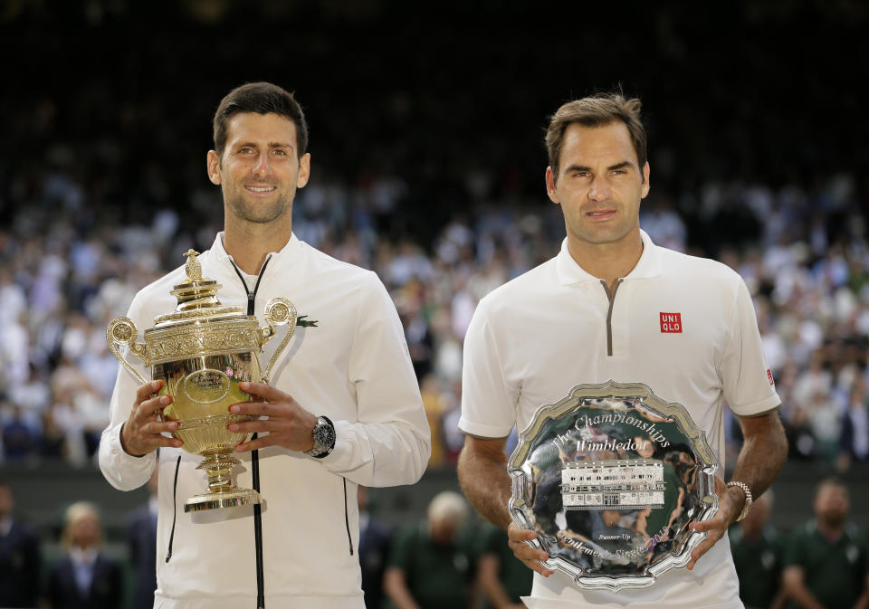 FILE - Serbia's Novak Djokovic, left, and Switzerland's Roger Federer pose with the trophies after the men's singles final match of the Wimbledon Tennis Championships in London, Sunday, July 14, 2019. He's already been No. 1 for more weeks than any man or woman in the half-century of computerized rankings. Now he will try to pull even with Roger Federer by earning title No. 8 at the oldest of the four Grand Slam tennis tournaments. (AP Photo/Tim Ireland, File)