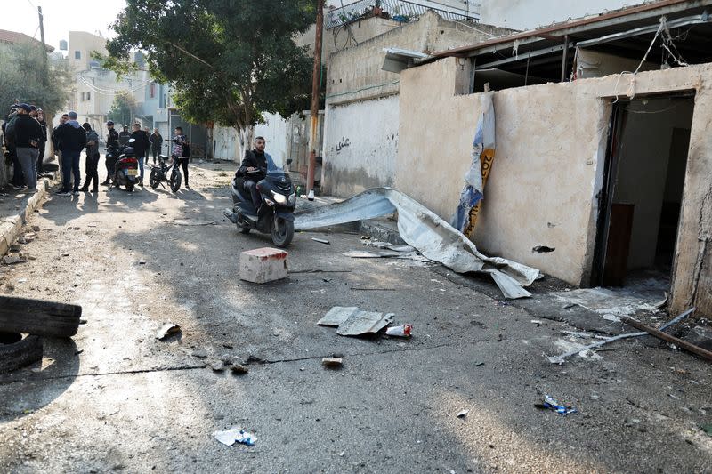 A man drives by a damaged house following a raid by Israeli forces, in Jenin