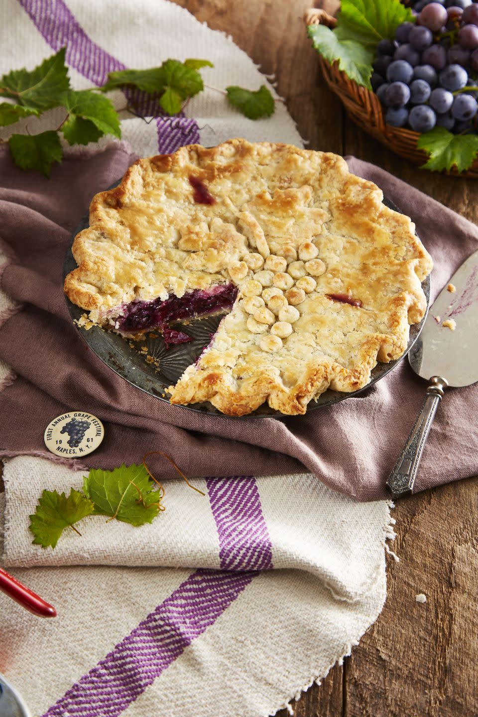 double crust concord grape pie with pie crust decorations on top that resemble a bundle of grapes
