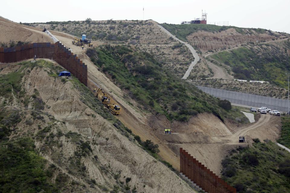 Construction crews replace a section of the primary wall separating San Diego, above right, and Tijuana, Mexico, below left, Monday, March 11, 2019, seen from Tijuana, Mexico. President Donald Trump is reviving his border wall fight, preparing a new budget that will seek $8.6 billion for the U.S-Mexico barrier while imposing steep spending cuts to other domestic programs and setting the stage for another fiscal battle. (AP Photo/Gregory Bull)