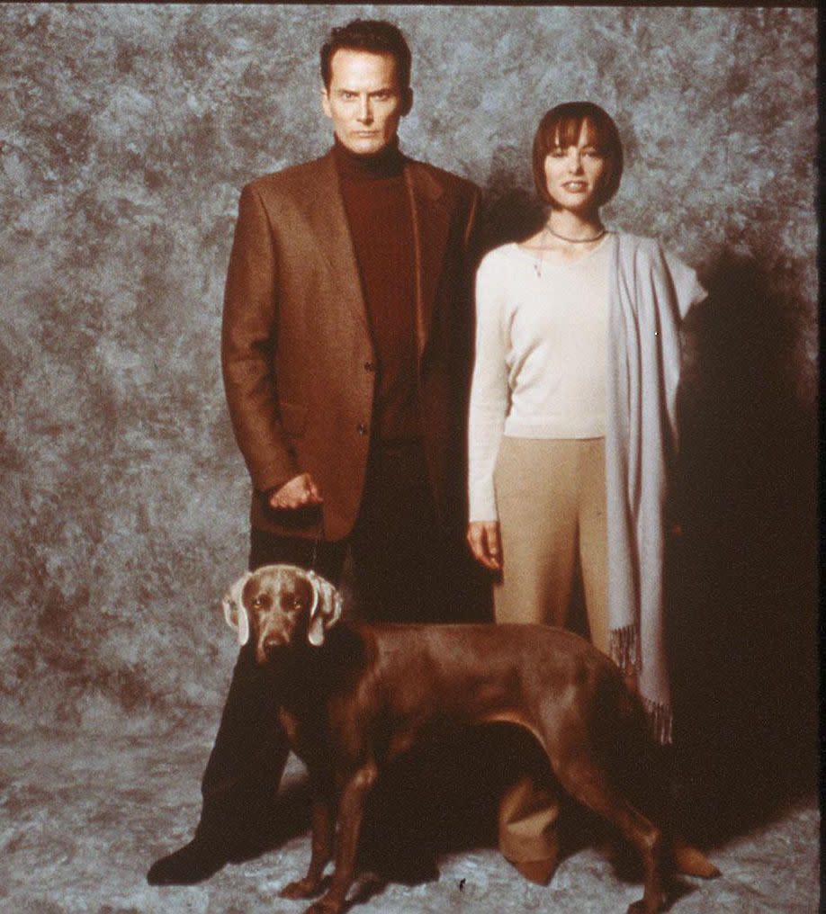 a man and a woman standing next to a dog