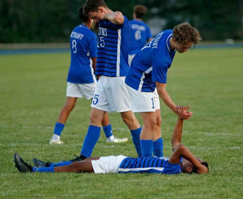 Bethany Christian senior James Lind extends his hand to teammate, senior Shemaya Magatti, after the Bruins lost to Mishawaka Marian, 1-0, on Monday, Aug. 28, 2023, at Bethany Christian High School in Goshen.