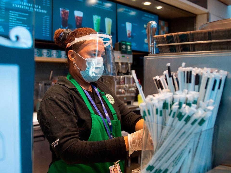 A Starbucks employee wears a face shield and mask as she makes a coffee in Ronald Reagan Washington National Airport in Arlington, Virginia, on May 12, 2020.