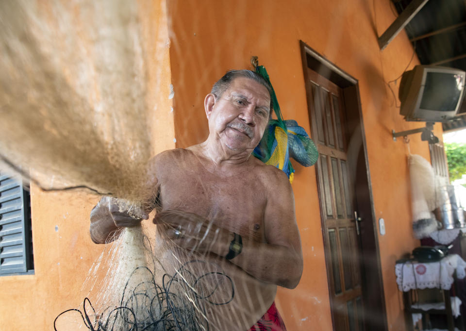 Fisherman Alfredo Jose Branco fixes his net at his home in Alter do Chao, district of Santarem, Para state, Brazil, Thursday, Aug. 27, 2020. Branco was born and raised in this once-isolated Brazilian Amazon district, a tropical paradise that blends dense rainforest and beaches by the clear waters of the Tapajós river. (AP Photo/Andre Penner)
