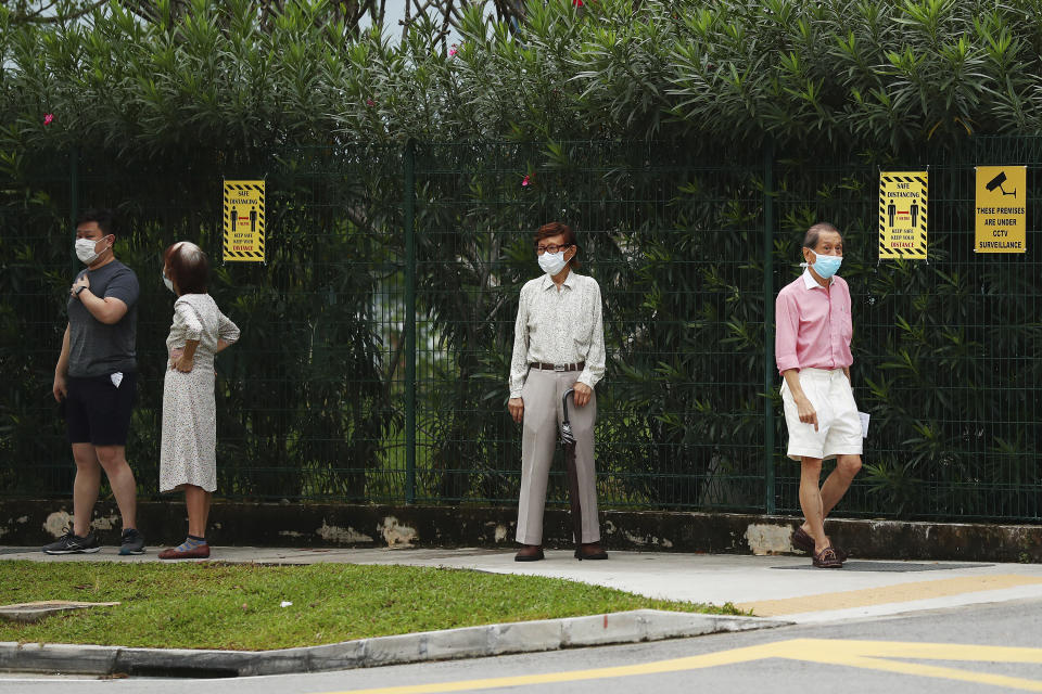 Voters wear face masks and observe social distancing as they wait to enter the Alexandra Primary School polling center in Singapore Friday, July 10, 2020. Wearing masks and plastic gloves, Singaporeans began voting in a general elections that is expected to return Prime Minister Lee Hsien Loong's long-ruling party to power. (AP Photo)