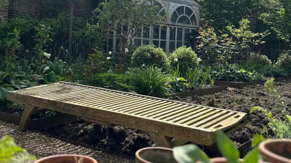 A wooden sunlounger in a garden