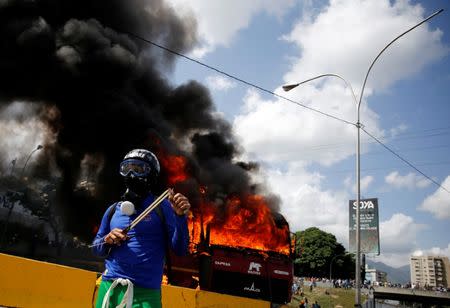 A demonstrator gestures as a truck set on fire burns on a highway during a rally against Venezuela's President Nicolas Maduro's Government in Caracas, Venezuela, June 23, 2017. REUTERS/Ivan Alvarado