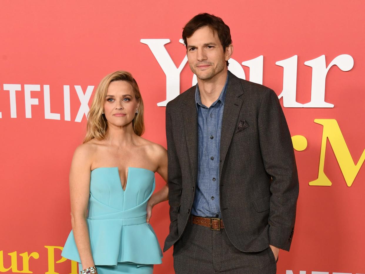 reese witherspoon and ashton kutcher at the your place or mine premiere. they're standing next to each other but not really posing together — witherspoon has her hand resting on her hip, while kutcher is standing a respectable distance away with his hands in his pockets