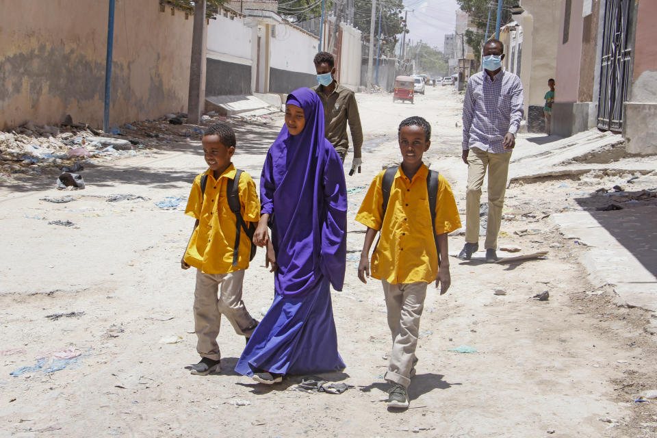 Somali schoolchildren walk home, while other people wear surgical masks, after the government announced the closure of schools and universities and banned large gatherings, following the announcement on Monday of the country's first case of the new coronavirus, in the capital Mogadishu, Somalia Wednesday, March 18, 2020. For most people, the new coronavirus causes only mild or moderate symptoms such as fever and cough and the vast majority recover in 2-6 weeks but for some, especially older adults and people with existing health issues, the virus that causes COVID-19 can result in more severe illness, including pneumonia. (AP Photo/Farah Abdi Warsameh)