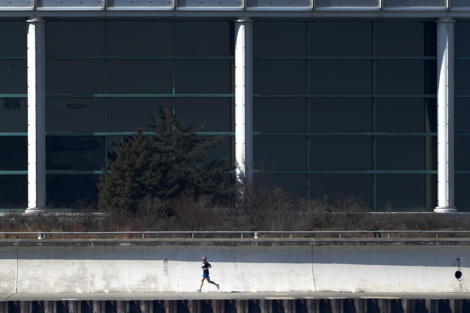 A runner passes the Shedd Aquarium along Lake Michigan Monday, Feb. 26, 2024, in Chicago. A warm front is sweeping spring-like weather across a large swath of the country in what is usually one of the coldest months of the year. The rare warmup is sending people out of their homes to enjoy the winter respite but also bringing increased wildfire danger. (AP Photo/Charles Rex Arbogast)