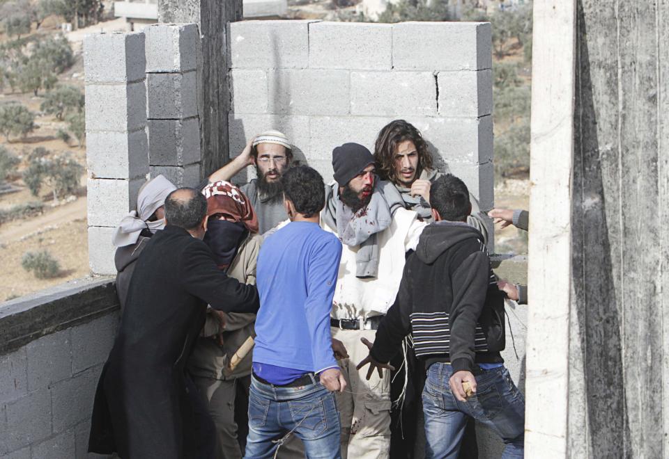 Palestinian villagers stand in front of Jewish settlers after they were detained Nablus