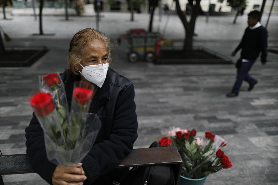 Wearing a mask to curb the spread of the new coronavirus, Martha Gonzalez Reyes, 76, sells roses outside Metro Hidalgo in central Mexico City, Monday, Aug. 10, 2020. After four months at home, Gonzalez returned to selling on August 1, but said business hasn't fully rebounded. "People have less money to spend, and they don't want to go out and get infected," said Gonzalez. (AP Photo/Rebecca Blackwell)