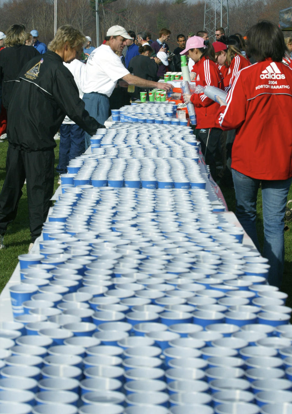 FILE - Runners pick up water in the athlete's village in Hopkinton, Mass. before the start of the Boston Marathon on Monday, April 19, 2004. Once a year for the last 100 years, Hopkinton becomes the center of the running world, thanks to a quirk of geography and history that made it the starting line for the world's oldest and most prestigious annual marathon. (AP Photo/Joe Giblin, File)