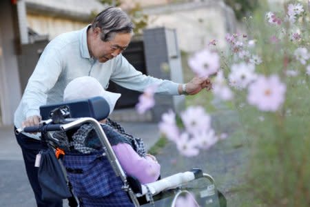 Eiichi Okubo (top), 71, speaks to his wife Yumiko, 68, who has been suffering from dementia, near her care house in Tokyo, Japan, October 29, 2018. REUTERS/Toru Hanai