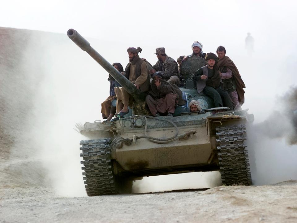 Taliban fighters sit on a tank.