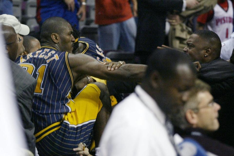 Indiana Pacers forward Ron Artest fights with a fan during a brawl at a game against the Detroit Pistons, in Auburn Hills, Mich., on Nov. 19, 2004. <a href="https://newsroom.ap.org/detail/NBAat75APWasThereMaliceatthePalace/e858811ee860456d882be6320dc9ec41/photo?Query=pistons%20pacers%20brawl&mediaType=photo&sortBy=arrivaldatetime:desc&dateRange=Anytime&totalCount=68&currentItemNo=2" rel="nofollow noopener" target="_blank" data-ylk="slk:Duane Burleson/AP Photo;elm:context_link;itc:0;sec:content-canvas" class="link ">Duane Burleson/AP Photo</a>