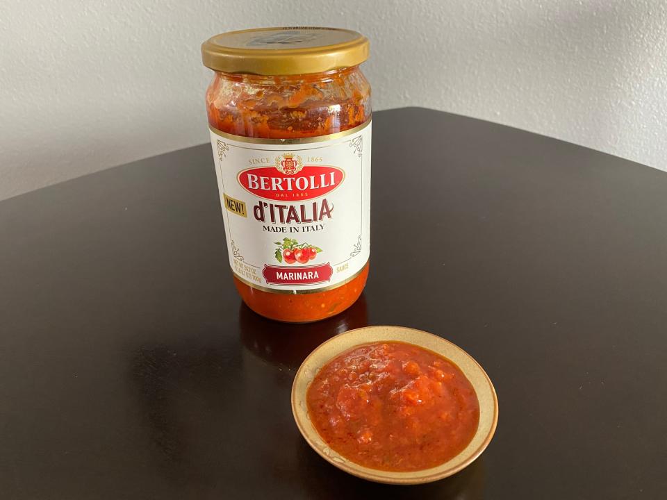 jar of bertolli red sauce with a small dish of the sauce in front of it