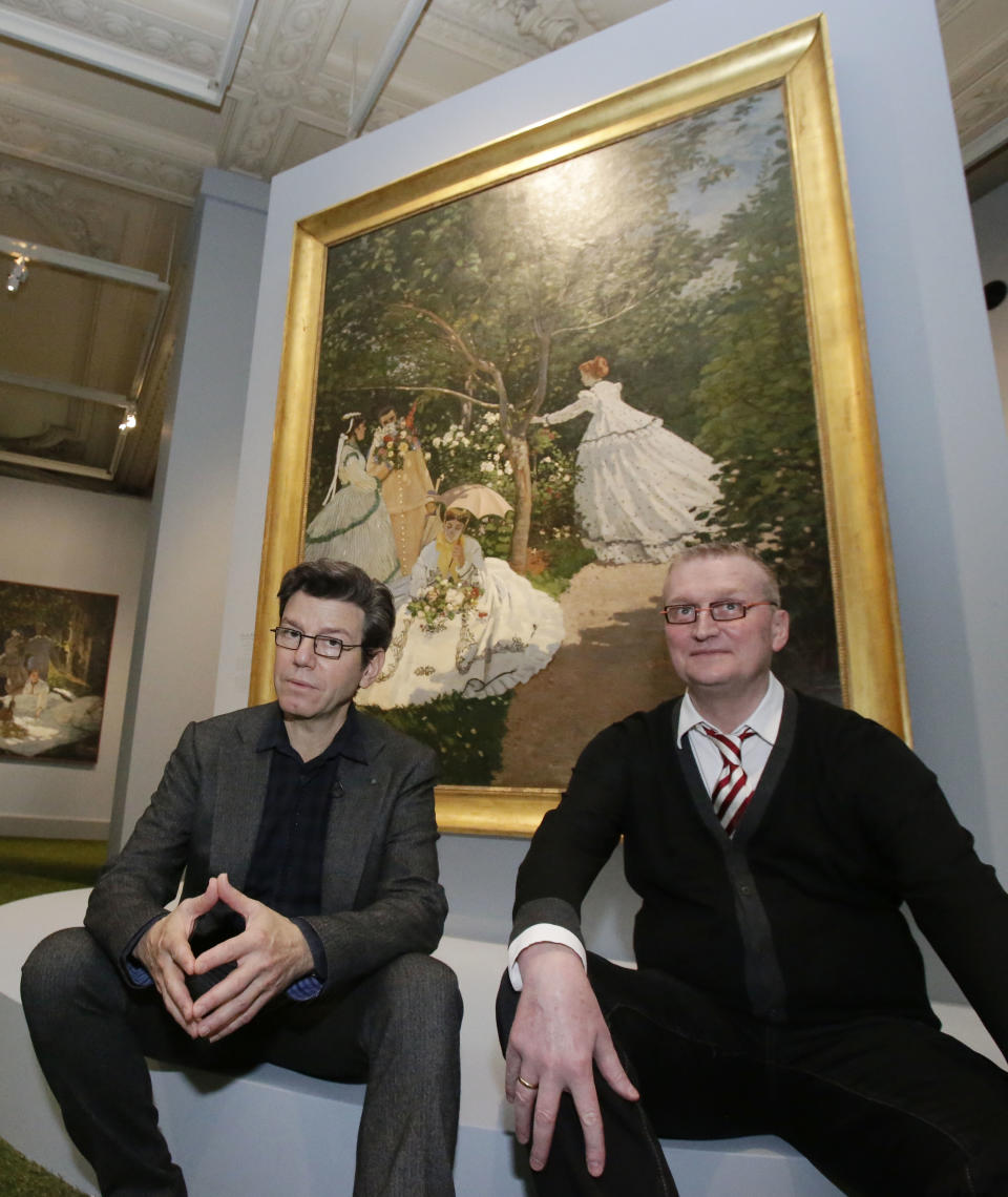 Exhibition designer, Robert Carsen, left, and head of the Musée d' Orsay, Guy Cogeva, right, pose for a photo in front of the painting of Gustave Caillebotte, Paris street, rainy day, 1877 during the press day of the Impressionism and Fashion exhibition in at the Orsay museum in Paris, Friday, Sept. 21, 2012. To coincide with Paris Fashion week, a new and highly original exhibit called "Impressionism and Fashion" opens at the Musee d'Orsay. It uses famous works of art to explore how at the dawn of impressionism, and as an emblem of "modernite" fashion, and how people dressed, became one of the main themes in art. The exhibition will open September 25, 2012 and last till January 2013. (AP Photo/Michel Euler)