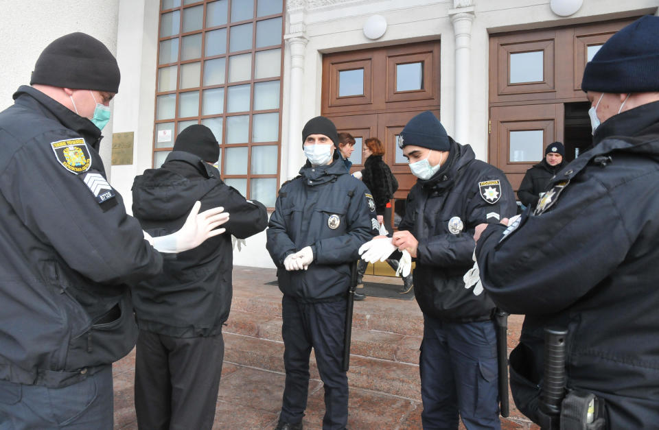 Ukrainian police officers prepare to secure an area next to busses with passengers from the Ukrainian aircraft chartered by the Ukrainian government for evacuation from the Chinese city of Wuhan, upon their landing at airport outside Kharkiv, Ukraine, Thursday, Feb. 20, 2020. Ukraine's effort to evacuate more than 70 people from China due to the outbreak of the new COVID-19 virus was delayed because of bad weather as evacuees travel to a hospital where they are expected to be quarantined. (AP Photo/Igor Chekachkov)