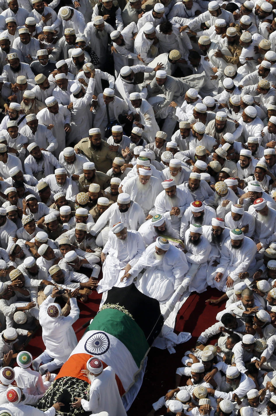 Indian Muslims crowd around the body of the head of the Dawoodi Bohra Muslim community Syedna Mohammed Burhanuddin during his funeral procession in Mumbai, India, Saturday, Jan. 18, 2014. A pre-dawn stampede killed more than a dozen people Saturday as tens of thousands of people gathered to mourn the death of Muslim spiritual leader Burhanuddin in the India's financial capital, police said. Burhanuddin died Friday at the age of 102. (AP Photo/Rajanish Kakade)