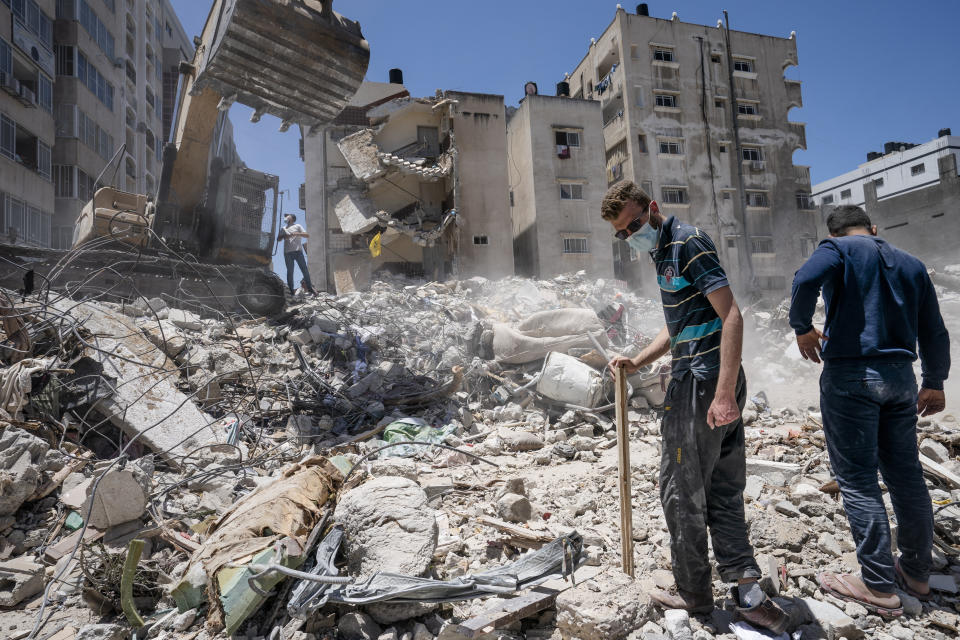 Heavy construction equipment is used to sift through rubble to uncover valuables before it is transported away from the scene of a building destroyed in an airstrike prior to a cease-fire that halted an 11-day war between Gaza's Hamas rulers and Israel, Thursday, May 27, 2021, in Gaza City. (AP Photo/John Minchillo)