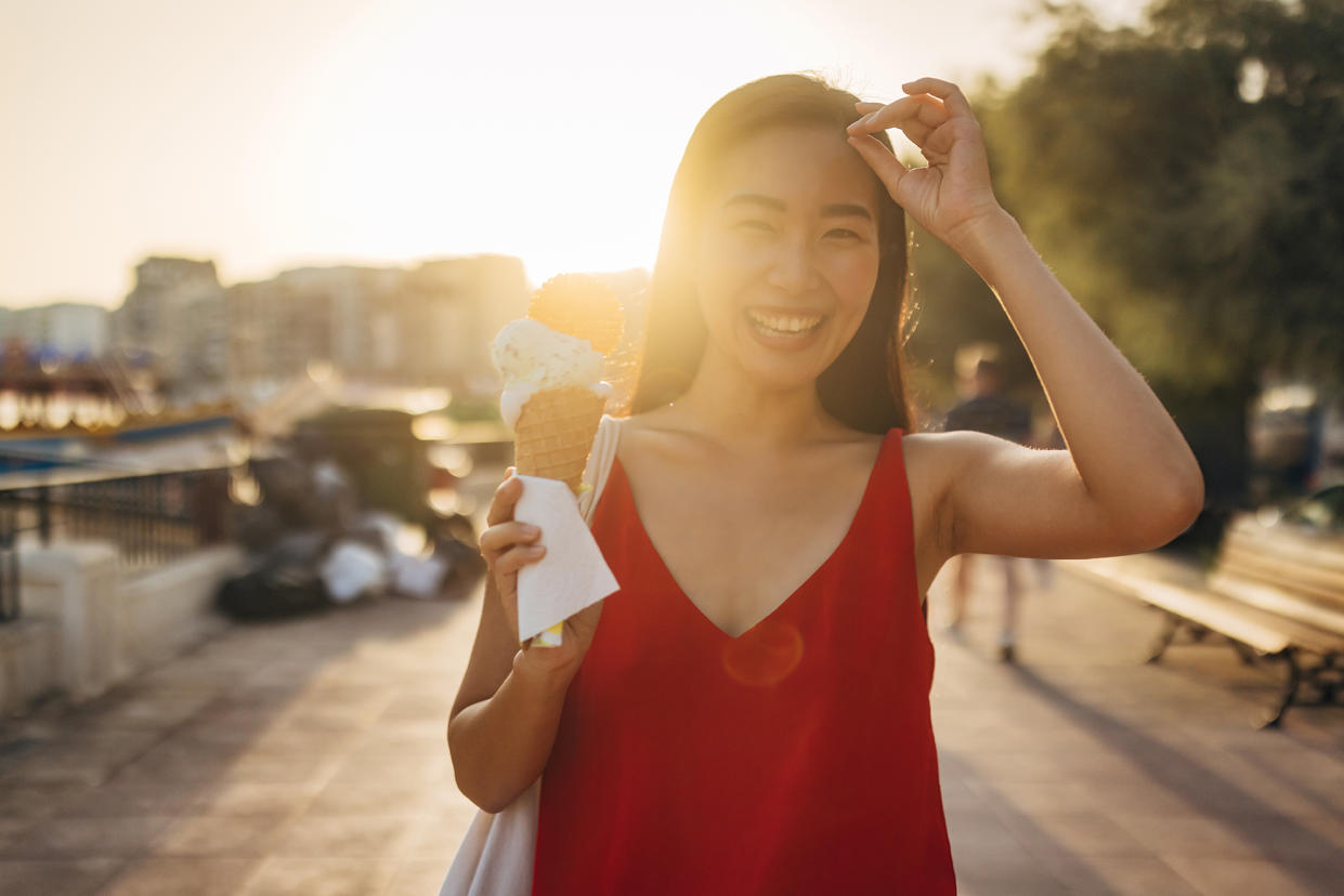 Portrait of a smiling woman eating ice cream and looking directly at the camera