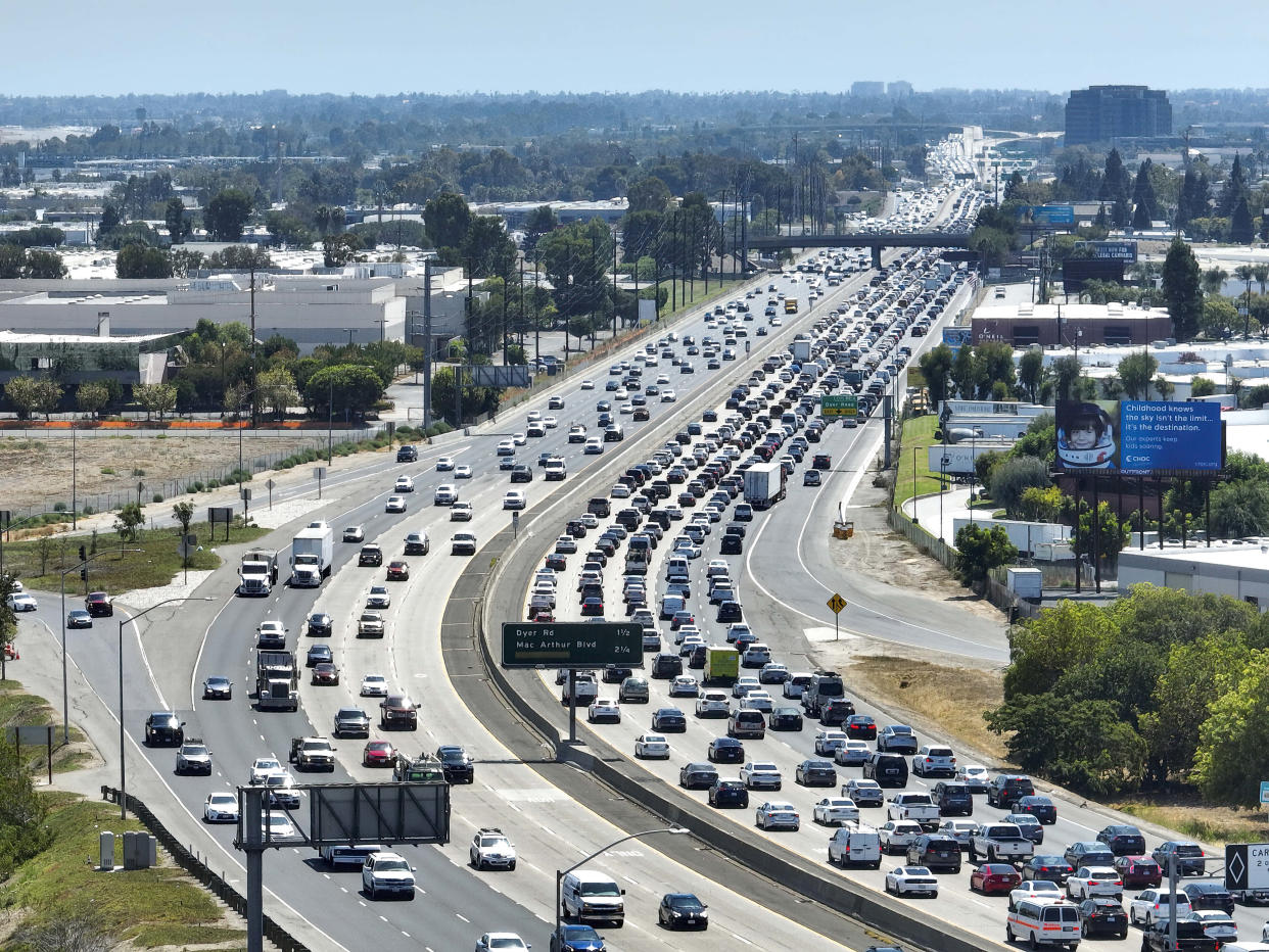 A packed freeway, with bumper-to-bumper traffic over five lanes on the right, wends its way through Santa Ana.