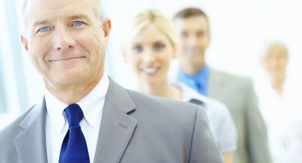 Closeup portrait of a happy senior business man with his blur team in background