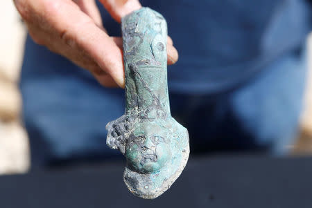 An Israel Antiquities Authority (IAA) employee holds an item, which the IAA estimates to be around 1600 years old, after it was recovered from a merchant ship in the ancient harbor of the Caesarea National Park May 16, 2016. REUTERS/ Baz Ratner