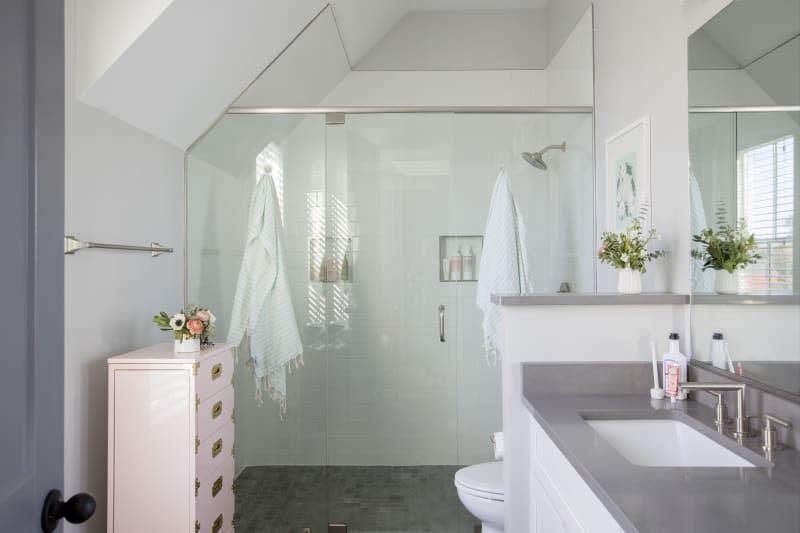 A bathroom with an A-frame ceiling and gray vanity top.