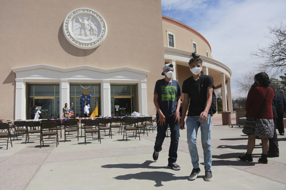 In this Monday, April 5, 2021, photo Jonathan Chilton, 14, center right, stands in front of the New Mexico state capitol ahead of a bill signing by the governor in Santa Fe, N.M. Chilton started school remotely on Tuesday following the Easter break. Around half of his classmates are now studying in-person, and he's not sure if he should go back with just a few weeks left in the semester. (AP Photo/Cedar Attanasio)