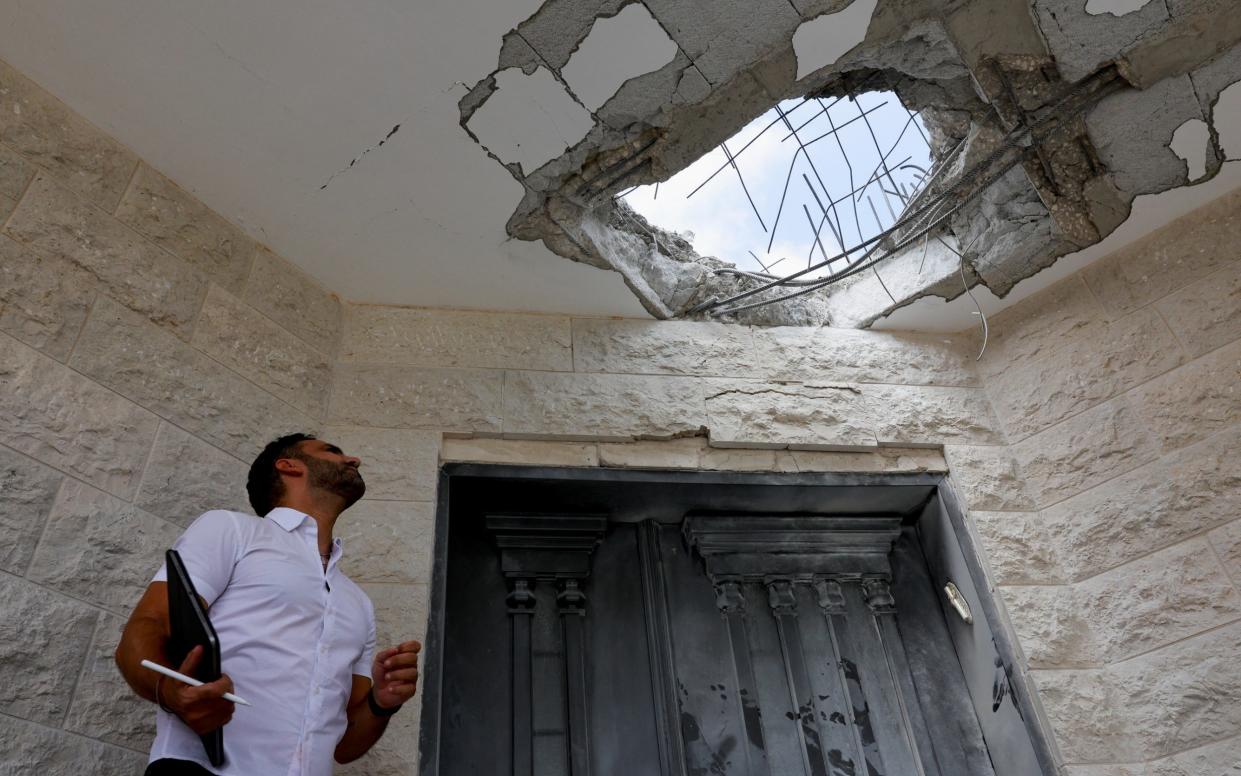 A man looks at the damage at a residential building following a direct-hit from a projectile, after Hezbollah launched hundreds of rockets