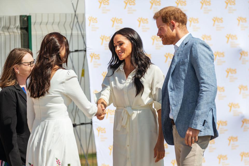 Meghan Markle and Prince Harry shaking hands with a charity worker in South Africa