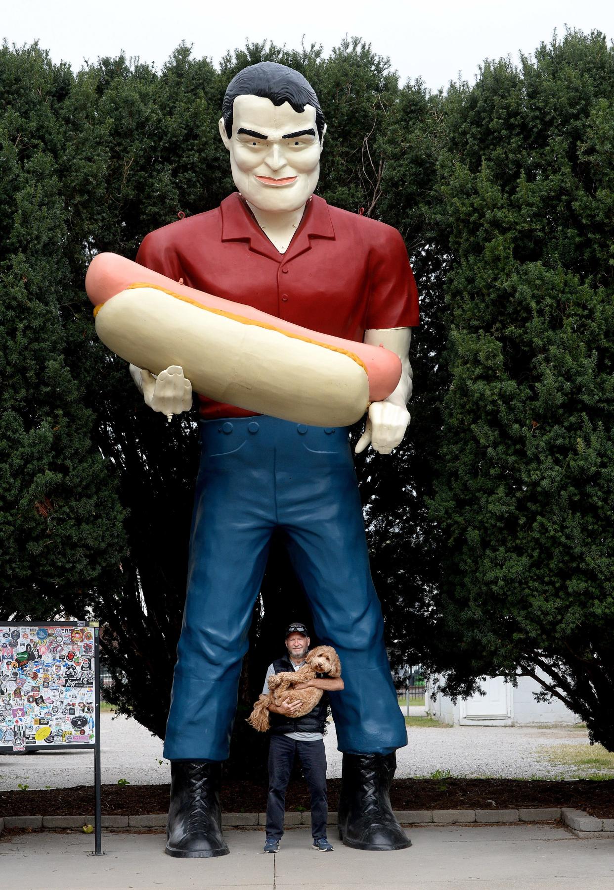 Steve Taggart of Prescott, Arizona, poses with his dog, Adeline, while his wife, Jamie, not pictured, takes their photo in front of the Hot Dog Man on Arch Street in Atlanta on Wednesday, Oct. 11, 2023. Down the street, the American Giants Museum opened this summer with a grand opening slated for next May.