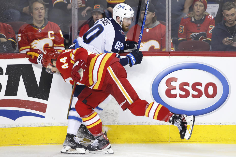 Winnipeg Jets' Pierre-Luc Dubois is hit by Calgary Flames' Erik Gudbranson during the second period of an NHL hockey game Saturday, Nov. 27, 2021, in Calgary, Alberta. (Larry MacDougal/The Canadian Press via AP)