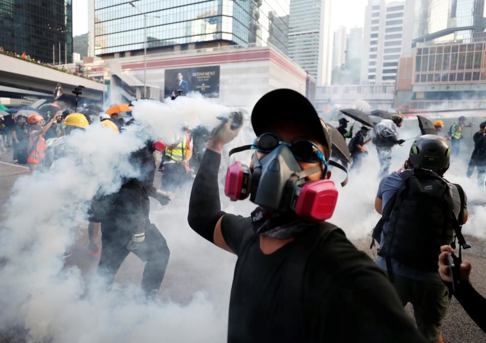 An anti-government protester throws back a tear gas canister at the police (Jorge Silva/Reuters)