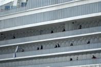 Some passengers look out from the balcony of the quarantined Diamond Princess cruise ship at a port in Yokohama, near Tokyo, Wednesday, Feb. 19, 2020. Hundreds of passengers began leaving the cruise ship Wednesday after the end of a much-criticized, two-week quarantine that failed to stop the spread of a new virus among passengers and crew. (AP Photo/Eugene Hoshiko)