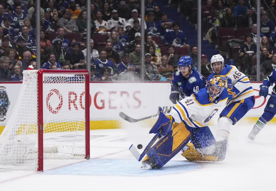 Buffalo Sabres goalie Craig Anderson (41) makes a save as Ilya Lyubushkin (46) checks Vancouver Canucks' Elias Pettersson (40) during the second period of an NHL hockey game Saturday, Oct. 22, 2022, in Vancouver, British Columbia. (Darryl Dyck/The Canadian Press via AP)