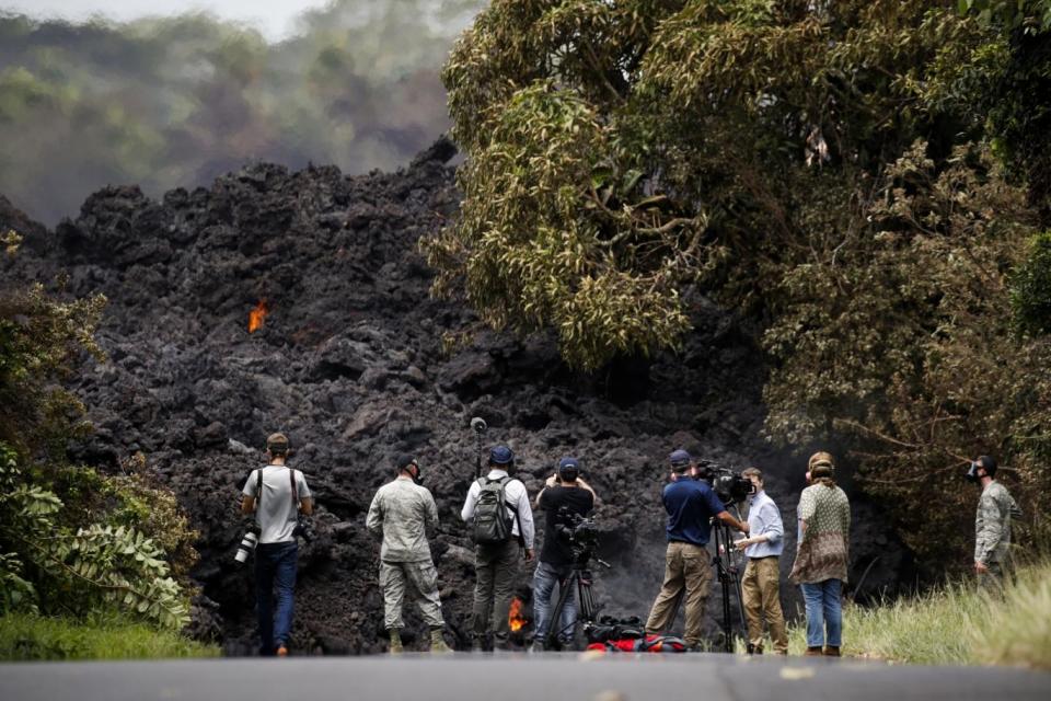 Members of the media record a wall of lava entering the ocean near Pahoa, Hawaii (AP)