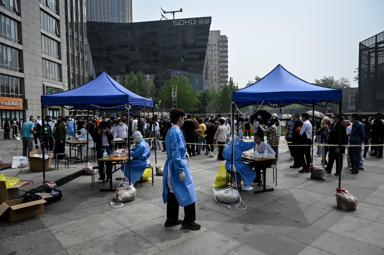 People line up to be tested for Covid-19 coronavirus at a makeshift testing site outside office buildings in Beijing on April 25, 2022. (Photo by Jade GAO / AFP) (Photo by JADE GAO/AFP via Getty Images)