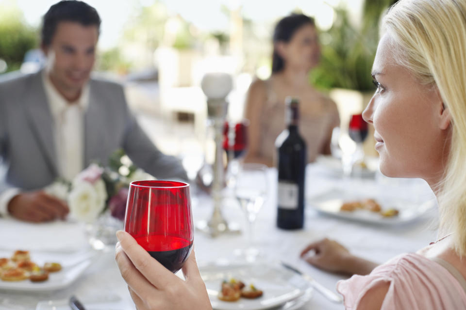 Young woman holding wineglass sitting at table with friends. Source: AAP