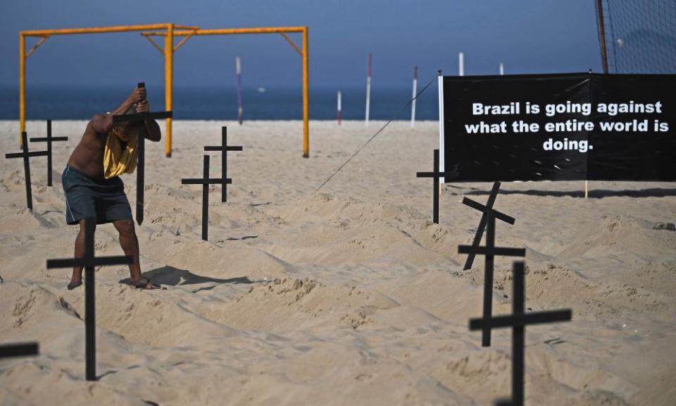 Marcio Antonio Silva, whose son died of coronavirus, re-erects one of 100 crosses built by activists symbolizing deaths from Covid-19 after a Bolsonaro supporter vandalized the memorial.