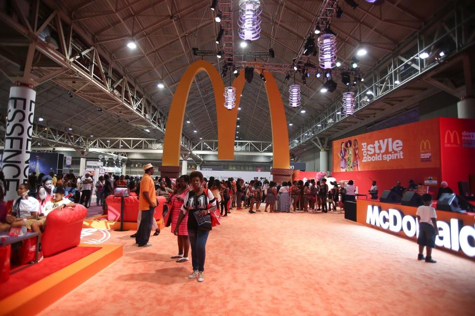 Golden Arches sign hanging from ceiling at a convention space, with McDonald's logo nearby.